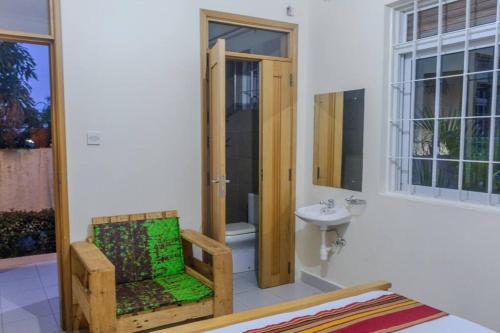 La salle de bains est pourvue d'un lavabo, de toilettes et d'une chaise. dans l'établissement The Greenleaf Luxury BnB -Lubowa, à Kampala