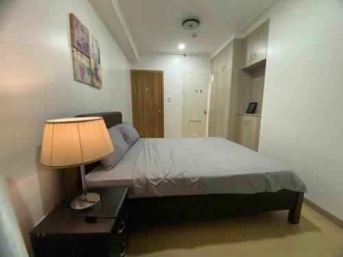 um quarto com uma cama e um candeeiro sobre uma mesa em SnugglePod Condotel - Grand Riviera Suites, US Embassy Manila, Roxas Blvd em Manila