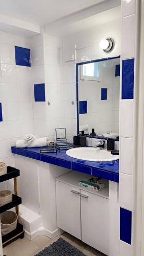 La salle de bains bleue et blanche est pourvue d'un lavabo et d'un miroir. dans l'établissement L’amazone, à Sannois