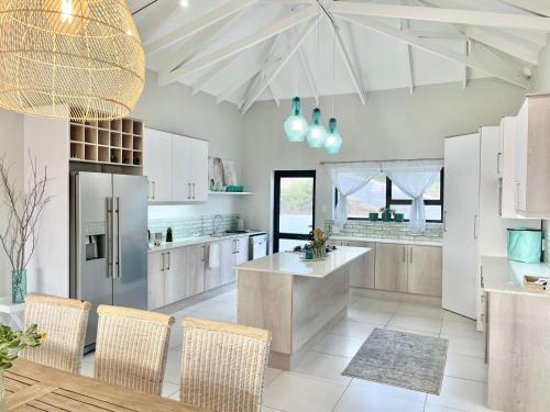 Una cocina con gabinetes blancos y una mesa y sillas. en Alchemy, en St Francis Bay