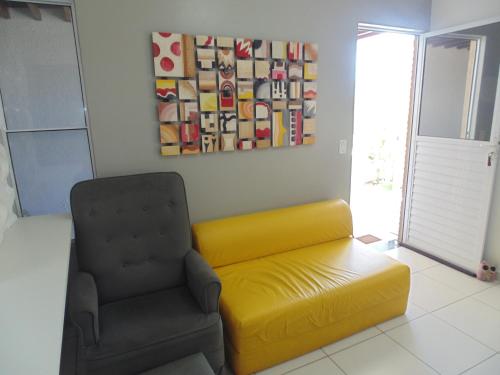 a living room with a yellow couch and a chair at Casa com Piscina em Condomínio Fechado na Praia do Francês in Marechal Deodoro