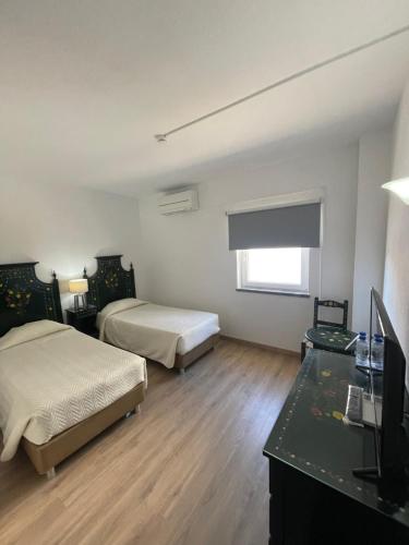 a room with two beds and a desk with a television at CASA DO PAÇO NOVO in Castelo de Vide