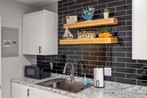 a kitchen with a sink and a black tiled wall at Lakeside Bliss 2BR, 1BA with All Modern Comforts in Algonac