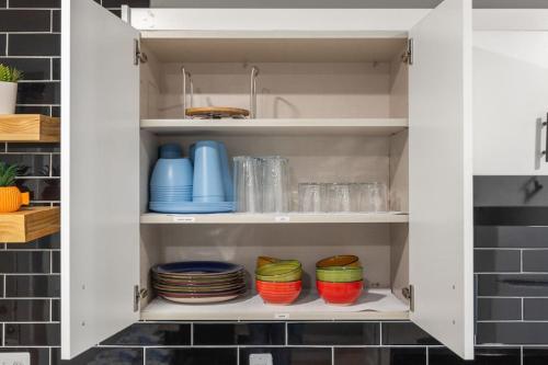 a kitchen cabinet with plates and bowls in it at Lakeside Bliss 2BR, 1BA with All Modern Comforts in Algonac