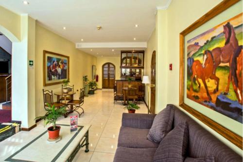 HOTEL DACARLO في سانتياغو: غرفة معيشة مع أريكة ولوحة على الحائط