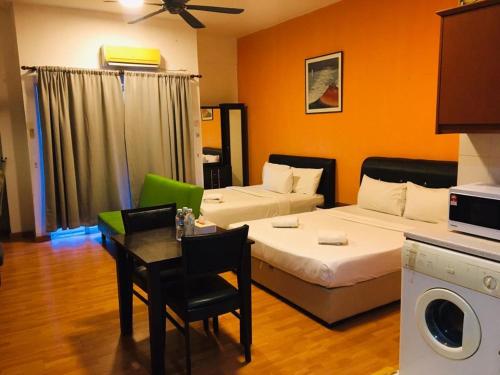 um quarto de hotel com duas camas e uma mesa e uma cozinha em Maytower Homestay HJN em Kuala Lumpur