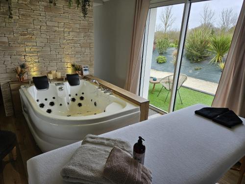 a bathroom with a bath tub and a window at L'Essentiel - Love 5 Etoiles in Talmont