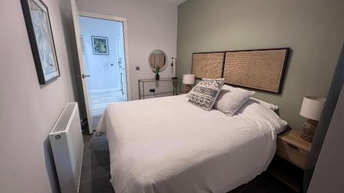 een slaapkamer met een wit bed met kussens erop bij St John's Apartments in Perth