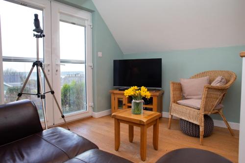 a living room with a television and a table with flowers at Vilureef Broad Haven in Broad Haven