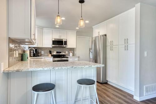 a kitchen with white cabinets and a counter with stools at Tranquility Base - Family Fun Modern Farm House in Dalton Gardens
