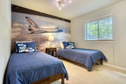 a bedroom with two beds and a mural of a plane at Tranquility Base - Family Fun Modern Farm House in Dalton Gardens