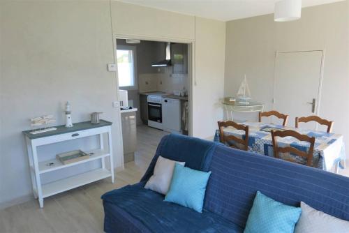 un salon avec un canapé bleu et une cuisine dans l'établissement Maison rénovée avec jardin clos et WIFI à PERROS-GUIREC - Réf 335, à Perros-Guirec