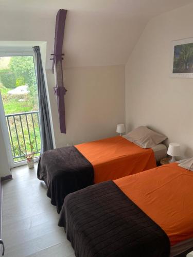 a bedroom with two beds and a large window at Ker Lann in Paimpont