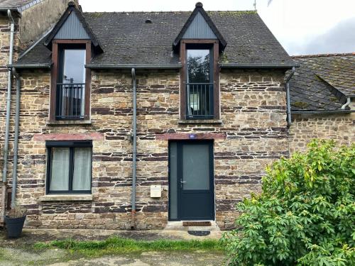 a brick house with a green door and windows at Ker Lann in Paimpont
