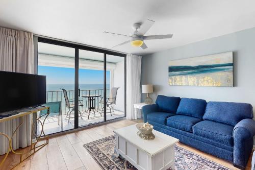 a living room with a blue couch and a balcony at Summerchase 1 in Orange Beach