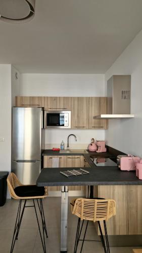 Il comprend une cuisine équipée d'un réfrigérateur et de chaises en acier inoxydable. dans l'établissement Le Malakoff, à Sérignan