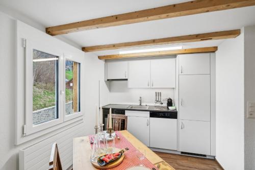 eine Küche mit weißen Schränken und einem Tisch in der Unterkunft Kuschelige Ferienwohnung direkt an der Skipiste in Wildhaus