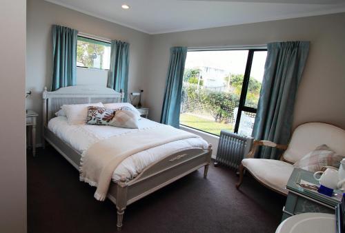 a bedroom with a bed and a window and a chair at Pacific View Bed and Breakfast in Wellington