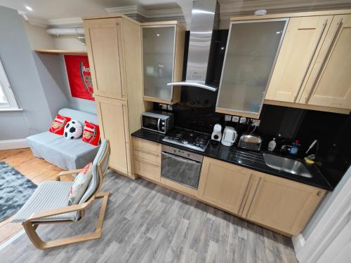 a kitchen with wooden cabinets and a chair in a room at LOVELY 1 BEDROOM FLAT IN FINSBURY PARK/EMIRATES STADIUM in London