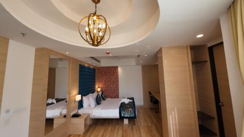 - une chambre avec un lit et un lustre dans l'établissement HOTEL SURYA GRAND, à Siliguri