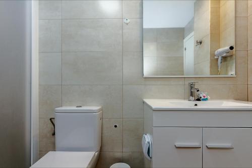 ein Badezimmer mit einem WC, einem Waschbecken und einem Spiegel in der Unterkunft Apartamento Seven Seas in Lloret de Mar