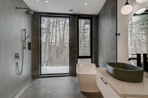 St-Etienne de Bolton的住宿－Au Haut De La Colline Spa Et Sauna，浴室配有黑色浴缸、盥洗盆和浴缸。