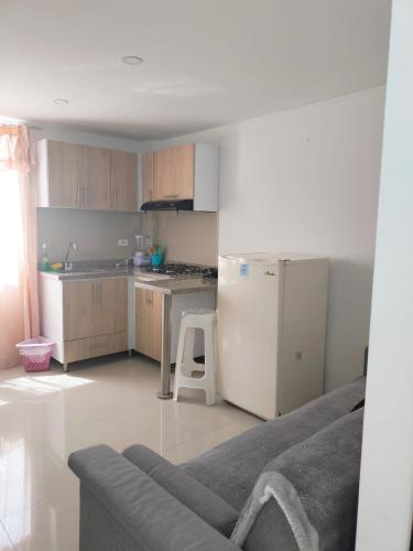 uma cozinha com um frigorífico branco e um sofá em Aparta-hotel medilaser-Uniboyaca em Tunja