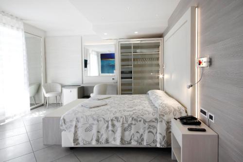 a white bedroom with a bed and a table at Grande Albergo Marin in Lignano Sabbiadoro