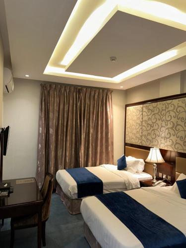 a hotel room with two beds and a desk at Maset Al Masem Apartments Units in Al Khobar