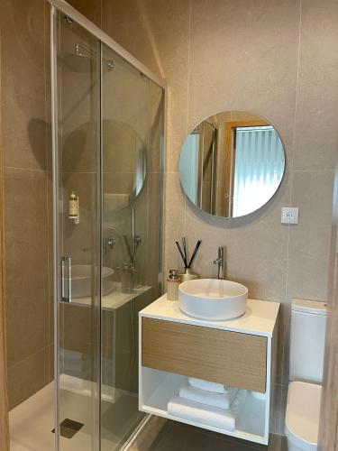 a bathroom with a sink and a shower with a mirror at OPORTO Suites in Moreira