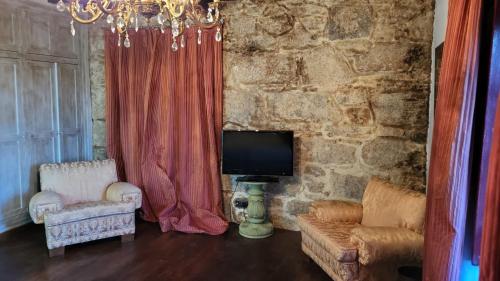 sala de estar con TV, sofá y sillas en Casa Rural del General Albelda, en Villasante