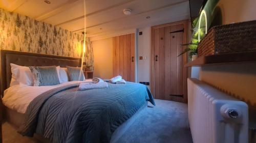 a bedroom with a bed with a blue comforter at Fox Corner, Ambleside, romantic retreat for two, dog friendly, hot tub in Ambleside