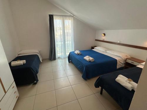 a hotel room with two beds and a window at Hotel Zamagna in Cesenatico