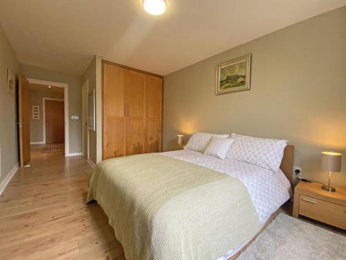 een slaapkamer met een groot bed en een houten vloer bij Apartment 453 - Clifden in Clifden