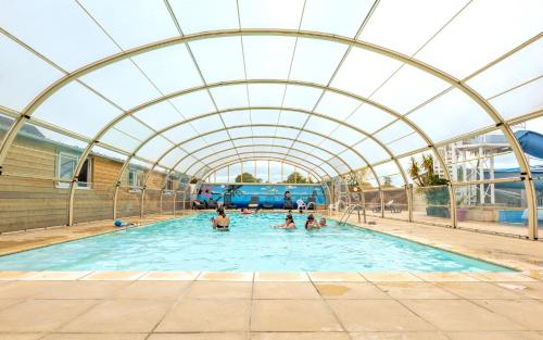 un grupo de personas en una piscina cubierta con sala de juegos en Camping Colleville-sur-Mer, en Colleville-sur-Mer
