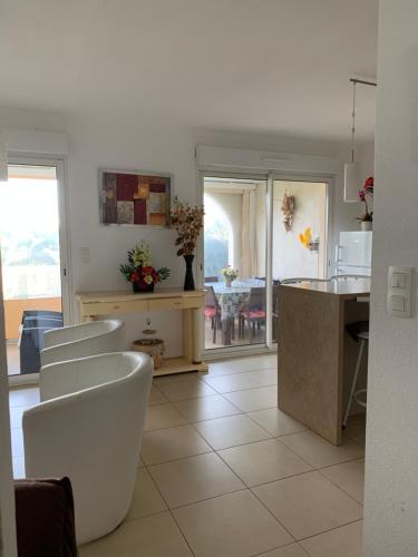 une cuisine avec des chaises blanches, un comptoir et une table dans l'établissement 3p, grd terrasse, jardin, centre-ville, 150m de la mer, à Algajola