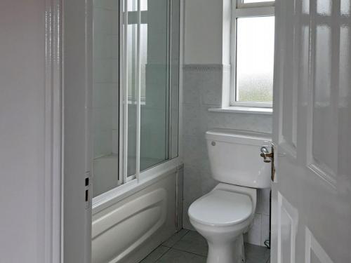 a white bathroom with a toilet and a window at Cottage 465 - Cashel in Carna
