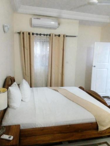 a bedroom with a bed with white sheets and a window at EKA ELITE HOTEL in Lomé
