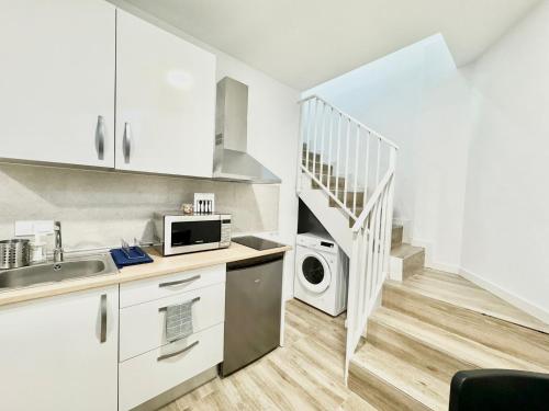 una cocina con armarios blancos y una escalera en Apartamentos Madrid Connection - Universidad by Oshun Apartments, en Madrid