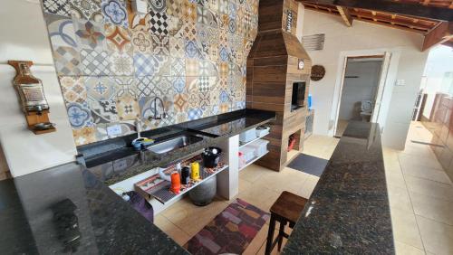 Una cocina con fregadero y pared de azulejos. en Casa com piscina e Wi Fi em Mongagua SP, en Praia Grande