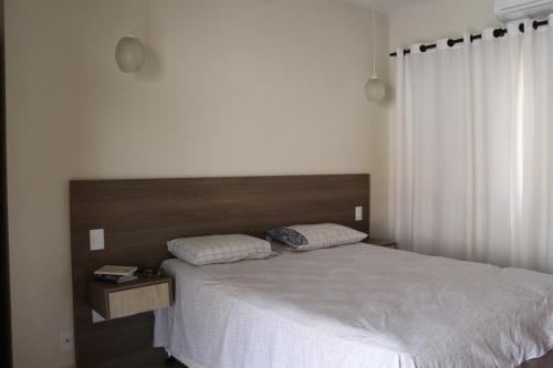 um quarto com uma cama branca e uma cabeceira em madeira em Casa bem localizada e de fácil acesso em Londrina