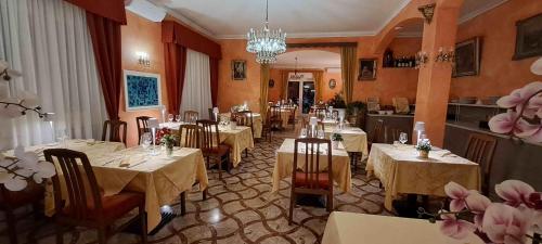 ein Restaurant mit Tischen, Stühlen und einem Kronleuchter in der Unterkunft Apartment Lake Maggiore - Gabella in Maccagno Inferiore