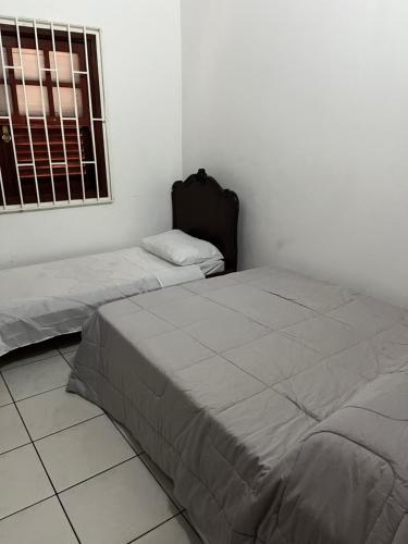 two beds in a white room with a window at Lindo Sítio na Serra Andradas a Poços de Caldas in Andradas