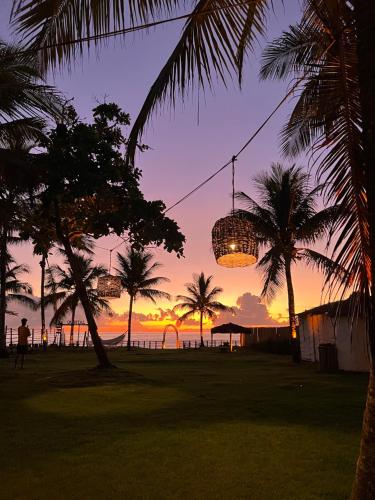 a sunset with palm trees and a chandelier at Pousada Quintal Caraíva in Caraíva