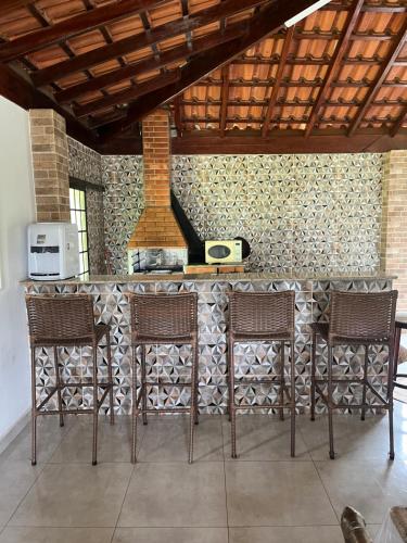 a kitchen with a counter with chairs and a stove at Lindo Sítio na Serra Andradas a Poços de Caldas in Andradas