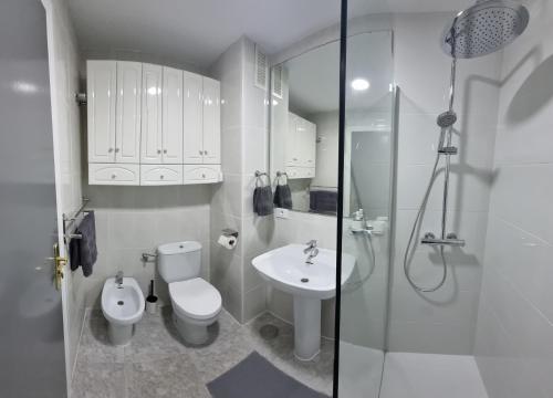 een witte badkamer met een toilet en een wastafel bij AYAHAY, Modern luxury apartment just 50 m from Playa Del Puerto in Puerto de Mazarrón