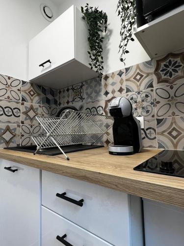 une cuisine avec des placards blancs et une cafetière sur un comptoir dans l'établissement Proche Centre Mulhouse - Studio cosy, à Mulhouse