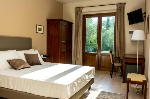 a bedroom with a bed and a desk and a window at Hotel & Spa Villa dei Mosaici in Spello