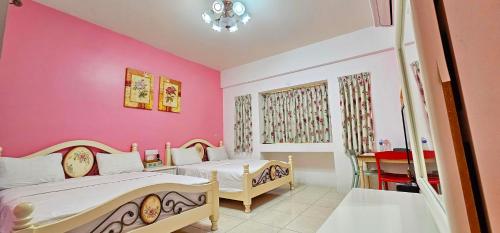 two beds in a room with pink walls at Loyofun in Donggang