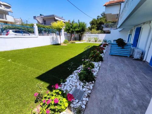 a garden with flowers and a yard with a house at Sea Breeze 201 in Skála Neón Epivatón